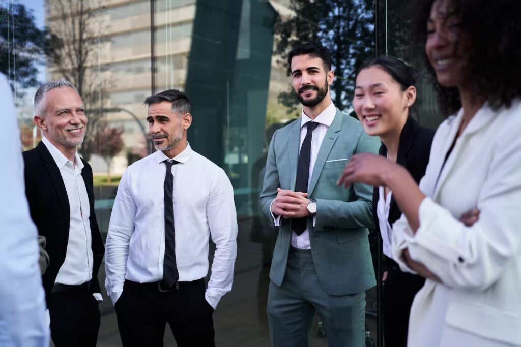 Grupo de profesionales frente a un edificio corporativo, símbolo de networking, crecimiento y éxito empresarial moderno.