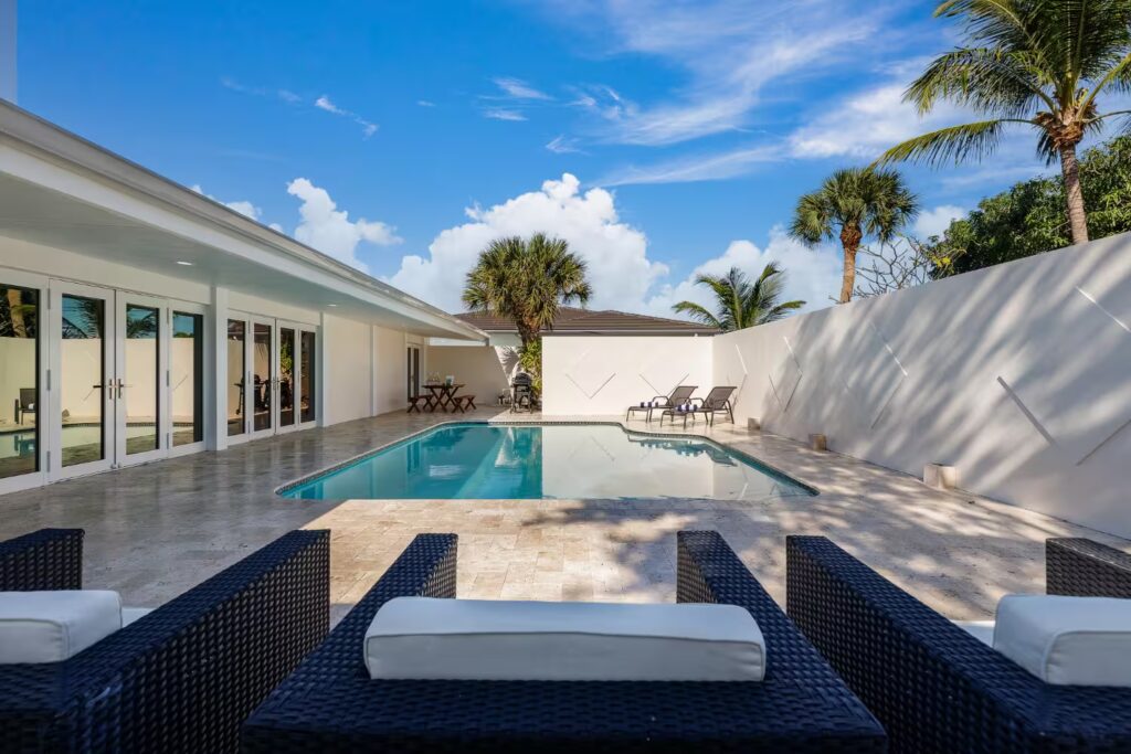 Front view of a modern house with pool and palm trees, representing contemporary architecture designed for warm climates.