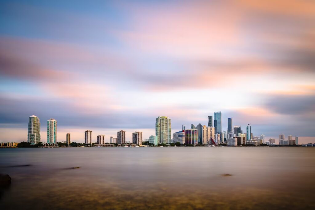 Panorámica del downtown de Miami, Florida, con rascacielos modernos e iluminación urbana reflejada sobre la bahía.