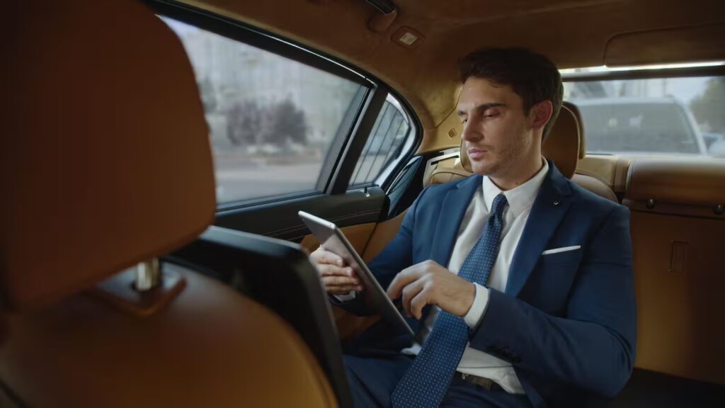High-net-worth investor analyzing portfolio and returns on a tablet in a luxury car.