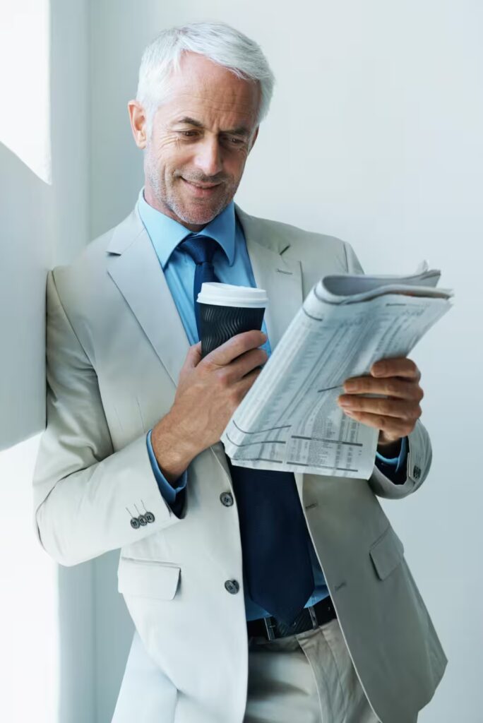 Investor reading financial papers and market news with coffee.